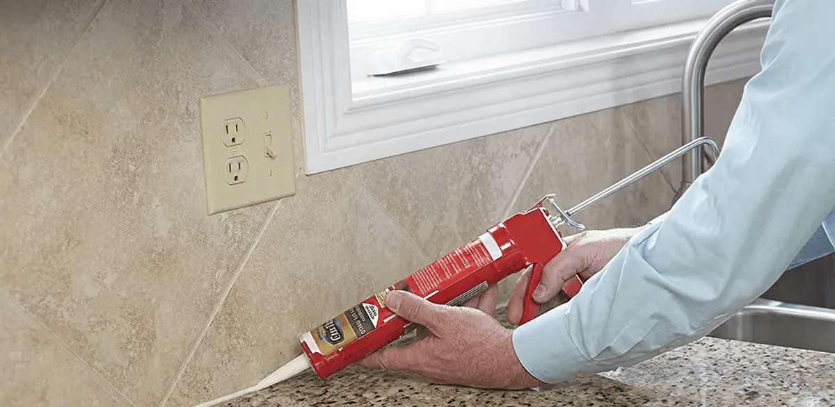 Handyman applying caulk along a kitchen backsplash and countertop seam in Dallas, TX